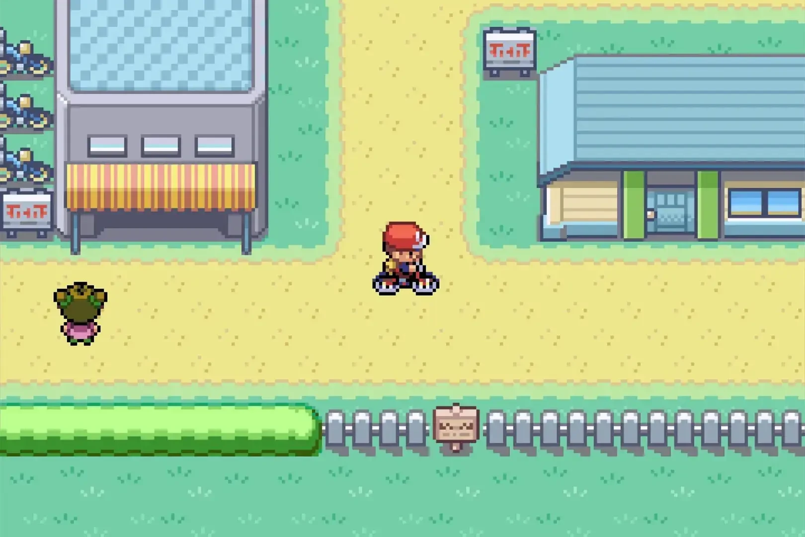 Pokémon Feuerrote Edition: Spielcharakter auf dem Fahrrad in einer Stadt mit Gebäuden und einem NPC in der Oberwelt